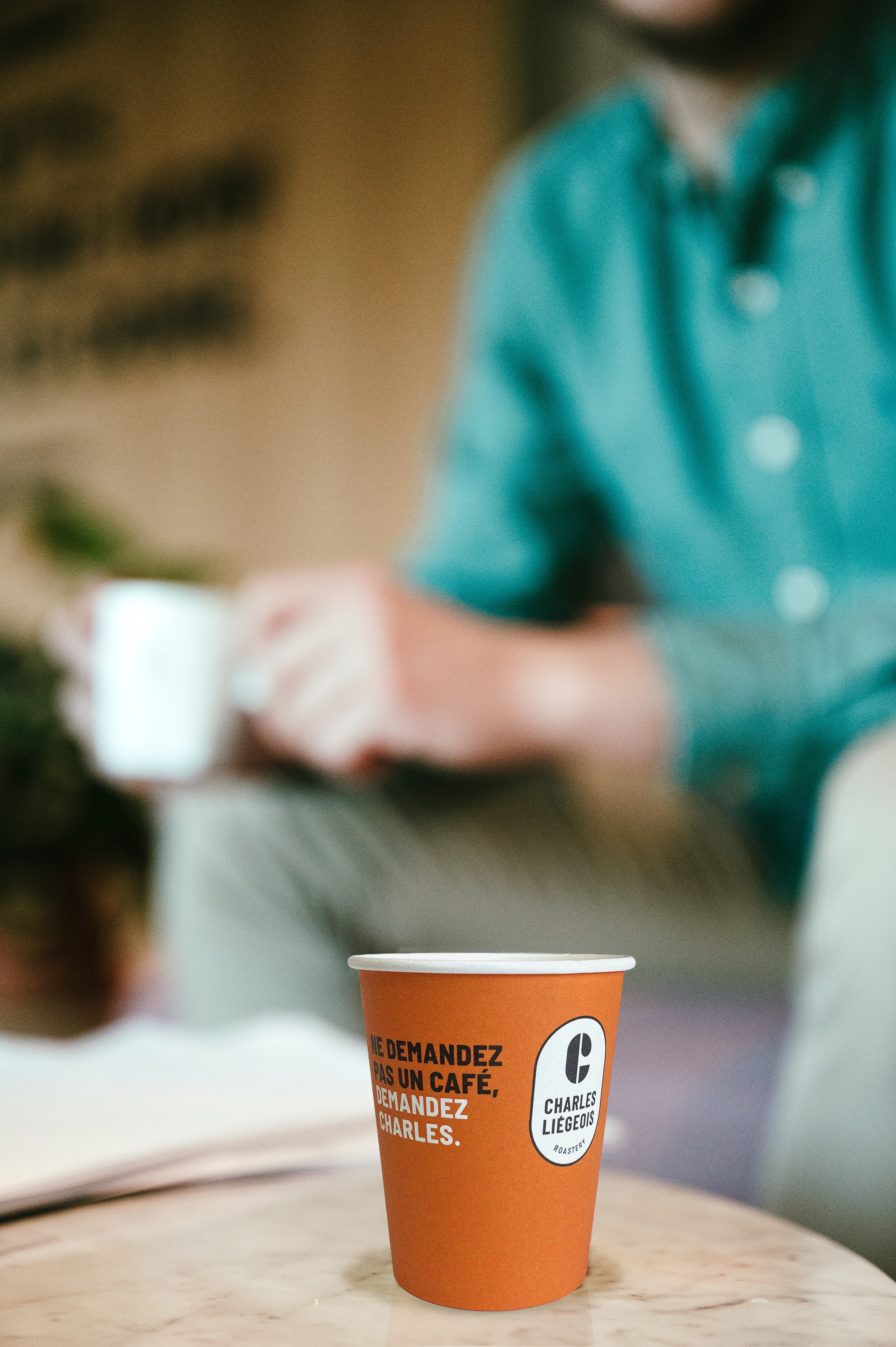 Gobelet orange de la torr&eacute;faction Charles Li&eacute;geois avec le slogan 'Ne demandez pas un caf&eacute;, demandez Charles', illustrant une pause caf&eacute; conviviale et qualitative en entreprise.